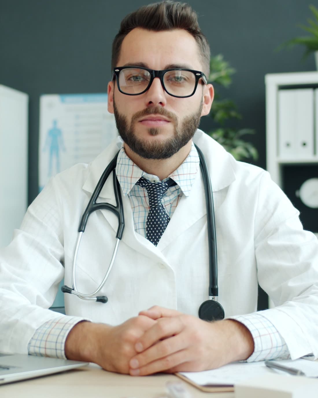 Médico de jaleco e estetoscópio na mesa do consultório